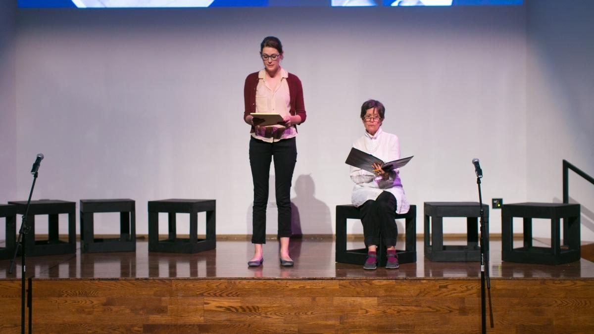 Two students on stage hold their screenplay scripts